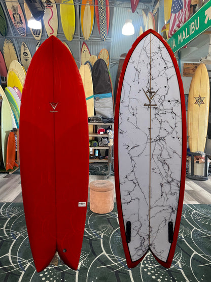 Two surfboards, one red and one with a white and black pattern, displayed indoors.