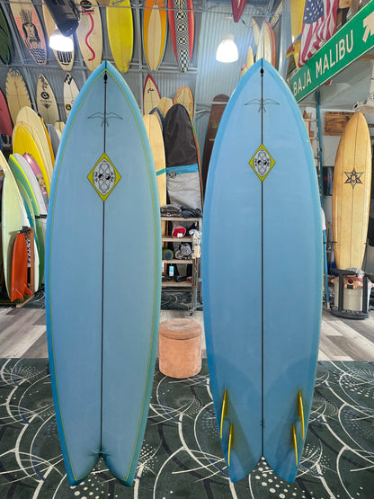 Two blue surfboards with yellow accents in a surfboard shop.