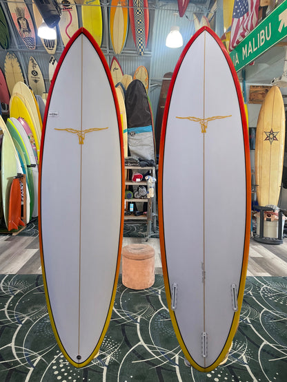 Two surfboards with a red and yellow design on a patterned floor, surrounded by various other surfboards.