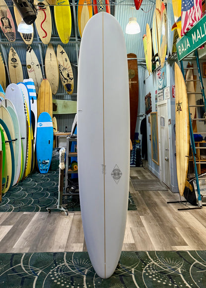 White surfboard in a store with various other surfboards on display.
