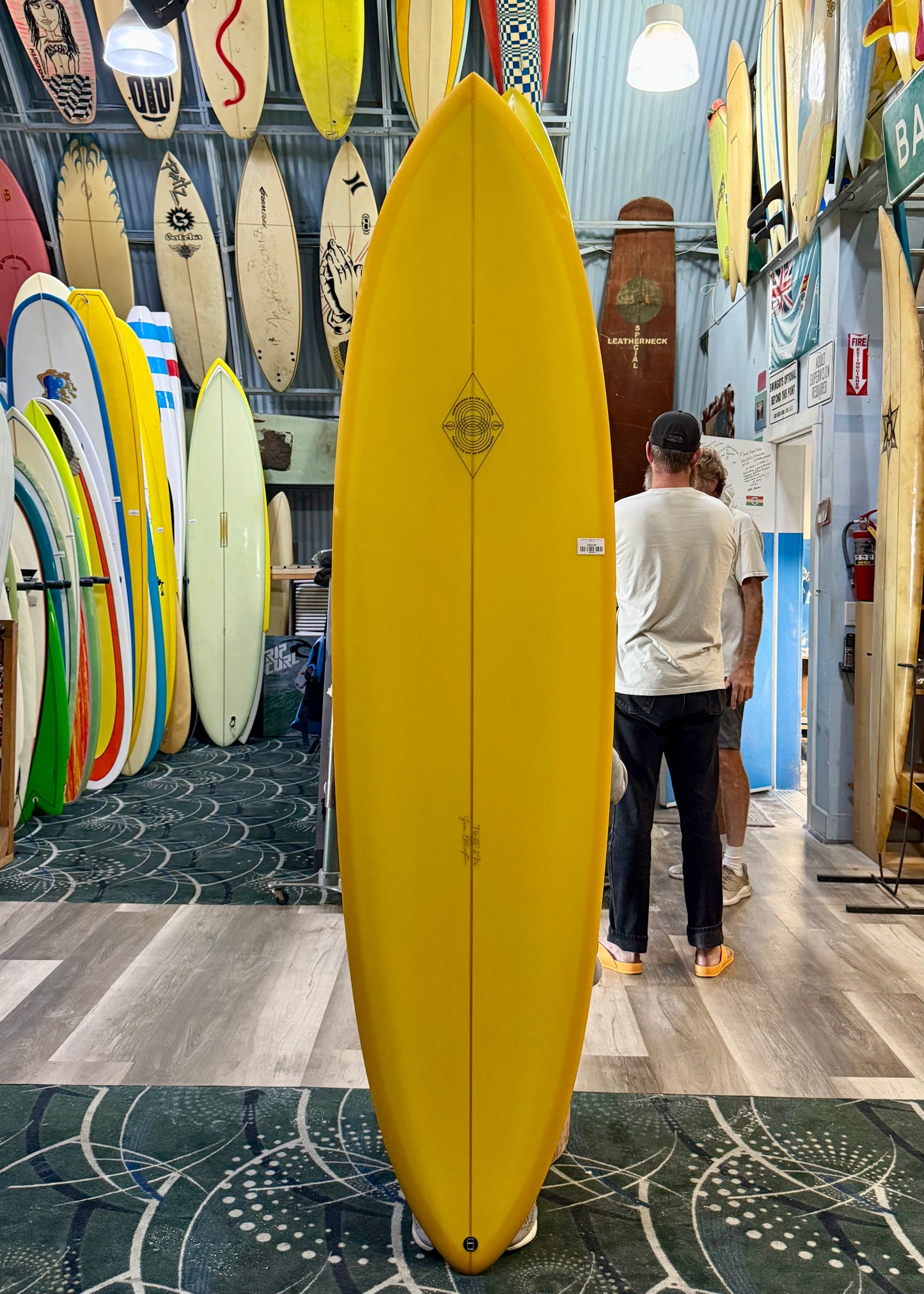 Yellow surfboard in a store with various other surfboards on display.