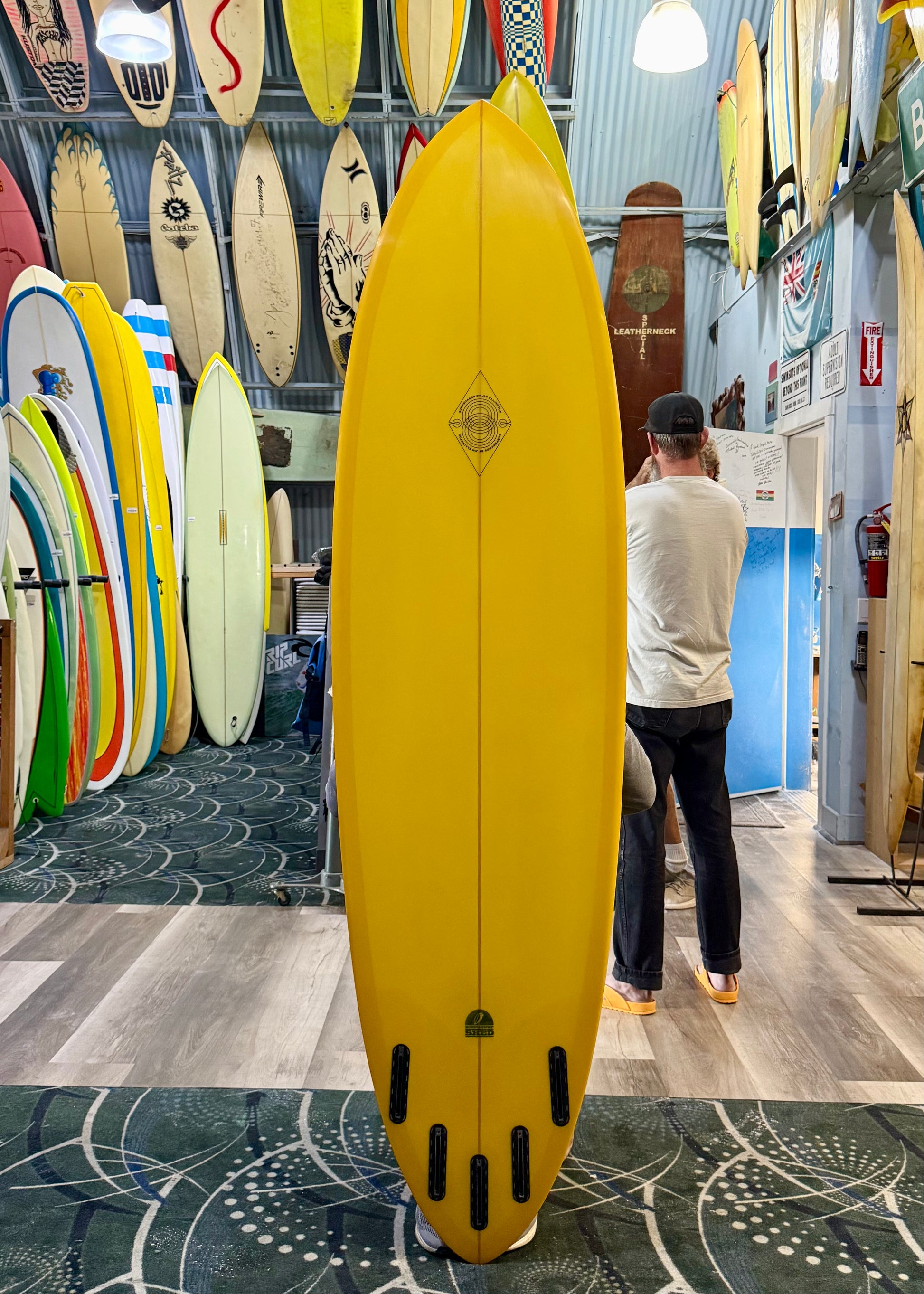 Yellow surfboard in a store with various other surfboards on display.