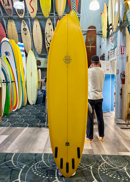 Yellow surfboard in a store with various other surfboards on display.