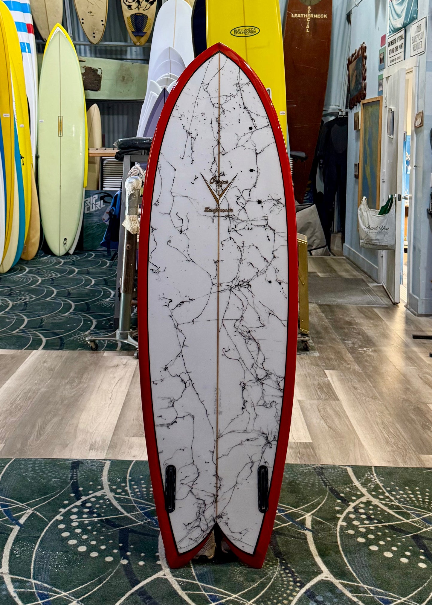 Marbled surfboard with red edges in a surf shop