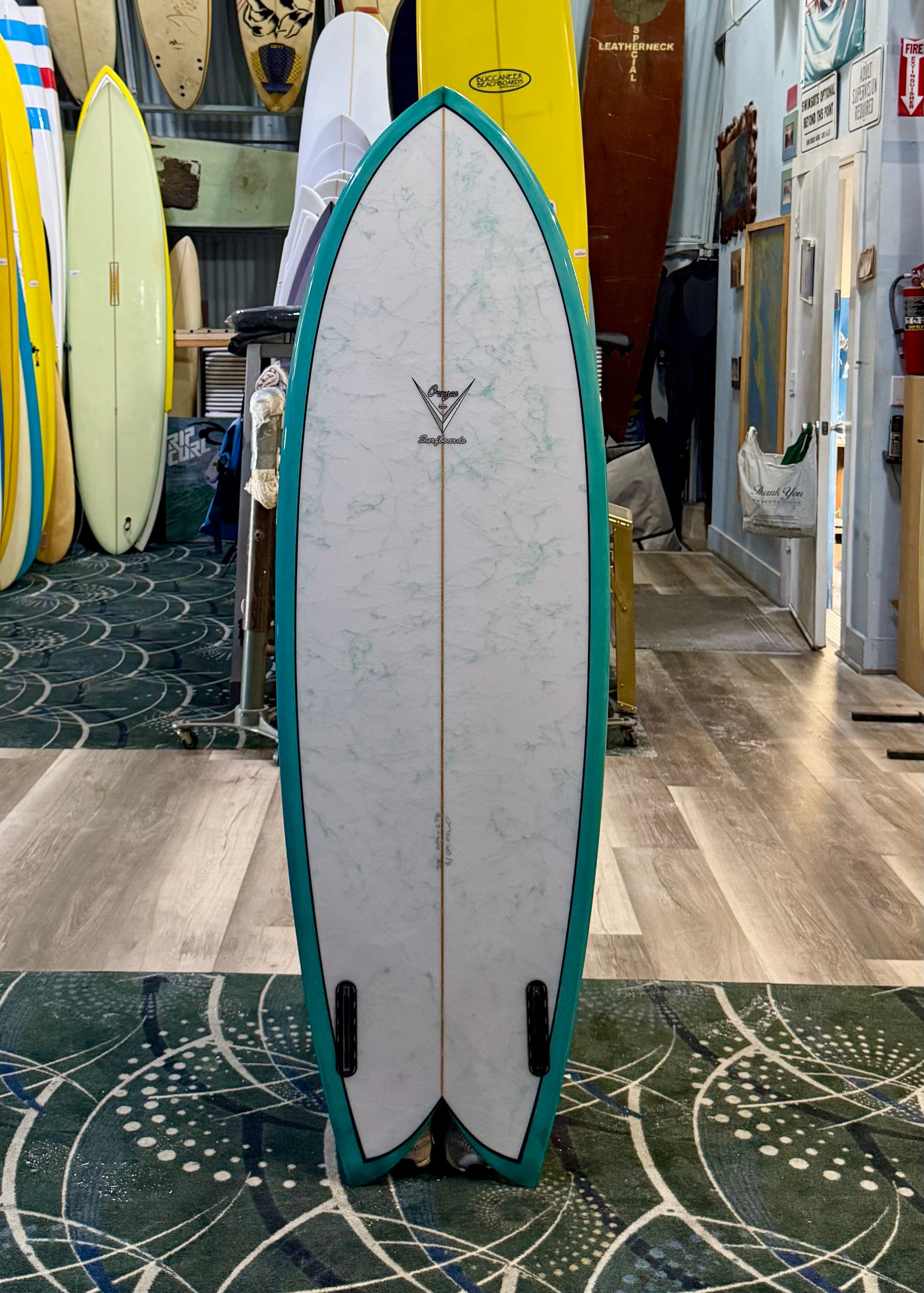 Surfboard with green and white design in a store setting