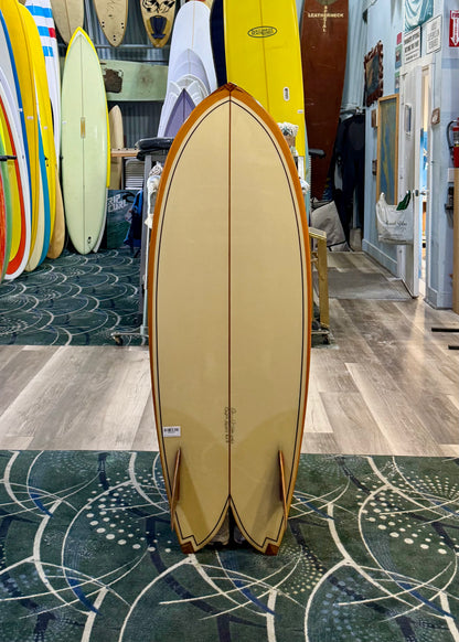 Beige surfboard with wooden edges on a stand in a store setting