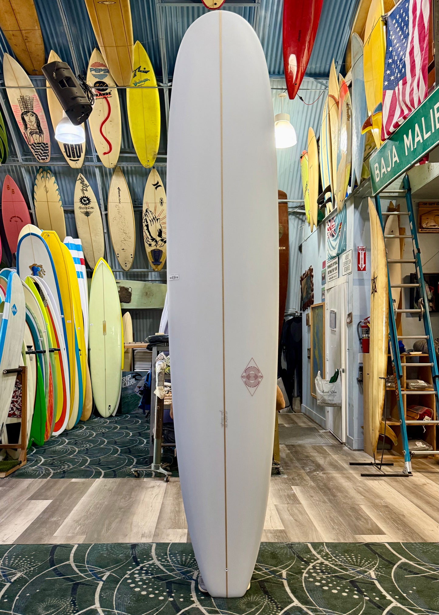 Surfboard in a shop with various surfboards and signs on the wall.
