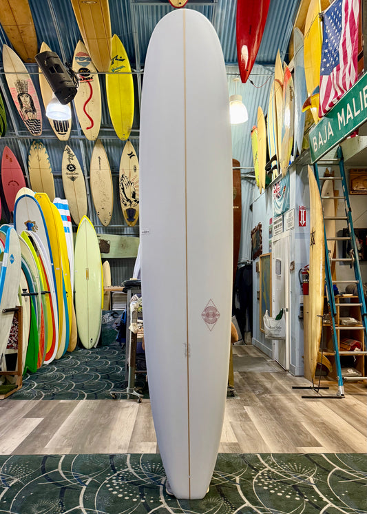 Surfboard in a shop with various surfboards and signs on the wall.